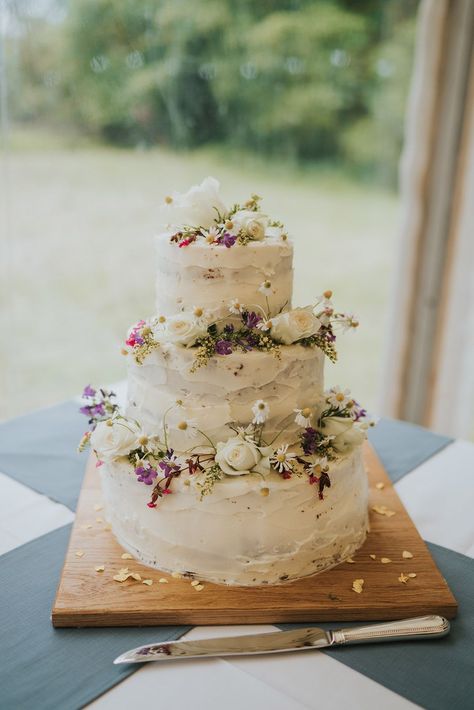 Three tier rustic white iced wedding cake with daisies and roses at marquee wedding Tiered Carrot Cake, Flowery Wedding Cakes, Meadow Wedding Cake, Wedding Cake Wild Flowers, Simple Wedding Cake Ideas 2 Tier, Wedding Ice Cream Cake, Real Flower Wedding Cake, Wedding Cake Wildflowers Simple, Wildflower Wedding Cake Rustic