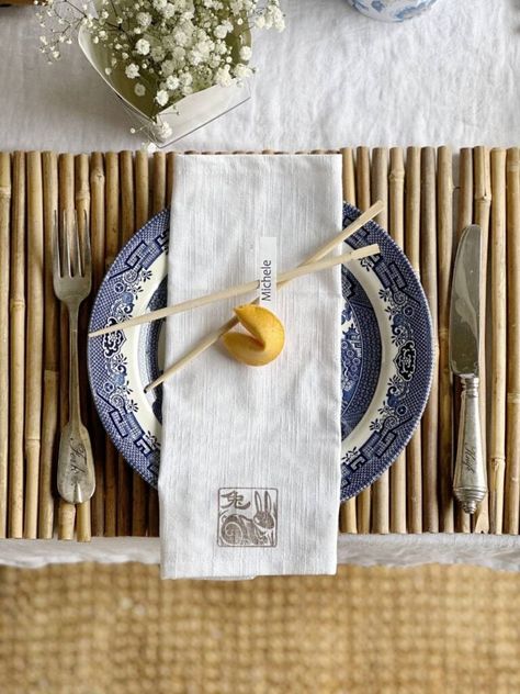 It's tablescape day for my dinner club and we're hosting an Asian inspired gathering. I'm sharing the best ideas for hosting a Chinese themed dinner party. My great grandmothers blue transferware with an Asian pattern was the inspiration for my Chinese themed table decor. Bamboo placemats, chopsticks, fortune cookies and Chinese takeout containers were other elements I incorporated. An Asian pattern teapot and the take-out containers made great vases for flowers for the centerpiece. Asian Table Setting Dinner Parties, Hibachi Party Table Setting, Japanese Inspired Tablescape, Chinese Takeout Party, Chinese Table Setting Ideas, Chinese Food Dinner Party, Asian Inspired Tablescape, Chinese Dinner Party Decorations, Chinese Table Decorations