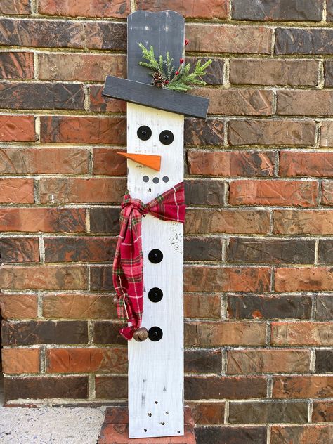 "These wooden snowmen yard or porch decorations are made using reclaimed pallet wood, painted white with a white wash effect. Scarf is fabric and will rival over time to add to the rustic effect.  The snowman has a red checkered scarf, with rustic jingle bells on the ends.  These snowmen can be propped up or be purchased with hardware to set in your yard. That would include the metal brackets as well as the metal post. These are sold separately but can be purchased as a set. Measurements: 34.5\"x5\" snowman 34\"x5.5\" snowwomen These are individuals and can be placed close to each other or apart. Due to the nature of using reclaimed wood, we can not guarantee each snowman will look the same as the picture. We will do our best to ensure that they match.  More in our shop: Decorative tray: h Diy Wooden Porch Signs, Wooden Snowman Diy, Pallet Board Crafts, Pallet Wood Christmas Decor, Front Porch Diy Ideas, Pallet Holiday Projects, Crafts With Bricks, Christmas Decor Pallet Wood, Wood Projects For Christmas