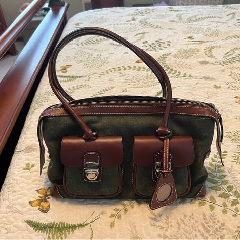 Beautiful Genuine Dooney And Bourke Purse With Hunter Green Canvas With Logo And Brown Leather Handles And Trim. 2 Pockets On Front, Zippered Top, Zippered Pocket On Back, Zipper Pocket Inside, 6 Feet On Bottom. Comes With A Key Fob, A Picture Triangle And A Separate Wristlet. 13“ W X 8“ H X 5 “ W. 10 “ Shoulder Handle Drop. This Is Brand New Without Tags. Never Used. Comes From A Clean And Smoke Free Home. Vintage Dooney Bourke Handbags, Wine Aesthetic, Europe Outfits, Green Purse, Brown Purse, Keychain Wallet, Dooney And Bourke, Dooney & Bourke Bags, Satchel Purse