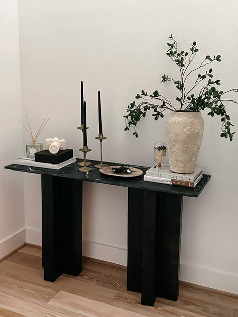 Entryway Console table decor Console Table : Burke Decor Vase : Pottery Barn Plant stems: Amazon Camera Candle : Gift from @kelir from CB2 Diffuser: Pottery Barn Black Candles: Amazon Candle Stand : Gift from @anniemescall Coffee Table Books : Amazon #homedecor #home #entrywaydecor #consoletable #homestyle Hallway Stand Entry Tables, Vase On Entryway Table, Black Console Decor, Walkway Table Decor, Small Black Entryway Table, Black Console Table Styling, Black Coffee Table Styling, Black Entry Table Decor, Console Decor Ideas