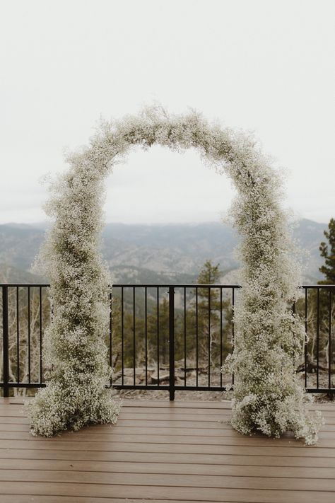 A oval wedding arch completely covered with babies breath flowers sits on a wooden deck with the mountains in the background. Babies Breath Arch, Black Table Linens Wedding, Wedding Aisle Decorations Outdoor, Sage Green Wedding Colors, White Wedding Arch, Floral Arch Wedding, Provence Wedding, Dream Wedding Decorations, Cottage Wedding