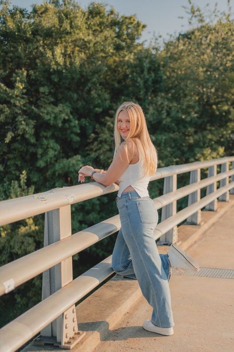 blond teen girl poses with one leg kicked back, smiling over her shoulder at the camera as she leans on a bridge railing. Indoor Senior Pictures, Casual Senior Pictures, Senior Outfit Ideas, Spring Senior Pictures, Senior Portrait Outfits, Senior Portrait Ideas, Senior Pictures Downtown, Senior Photoshoot Poses, Senior Portraits Girl