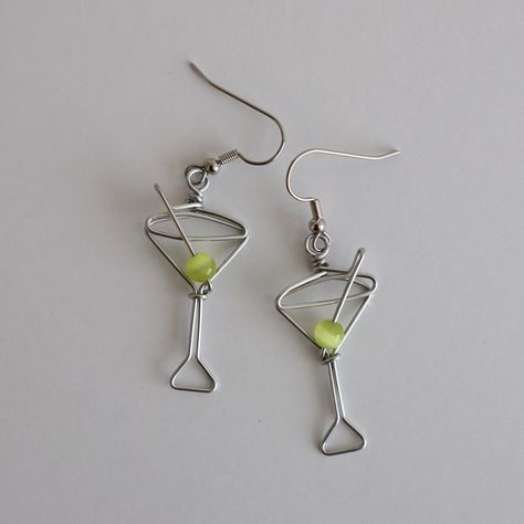 Martini Glass Earrings. Great gift for Bartenders, Hostesses and Waitresses. NOW AVAILABLE IN TWO SIZES. Regular martini glass is 1 1/2 inches high, small martini glass is 1 1/8 inches high (not including earring hooks, see inset photo for scale). Tiny wire martini glasses, complete with green cat's eye bead.  Surgical steel hooks are hypo-allergenic. Clear plastic stoppers on backs. Aluminum wire will not tarnish. I have been making custom wire art and jewelry for 30 years. I started in 1989 se Unique Earring, Wire Earring Designs, Stud Wire Earrings, Earrings Wire, Wire Earring Ideas, Christmas Wire Jewelry, Wired Earrings, Wire Earrings Diy, Wire Jewelry Ideas