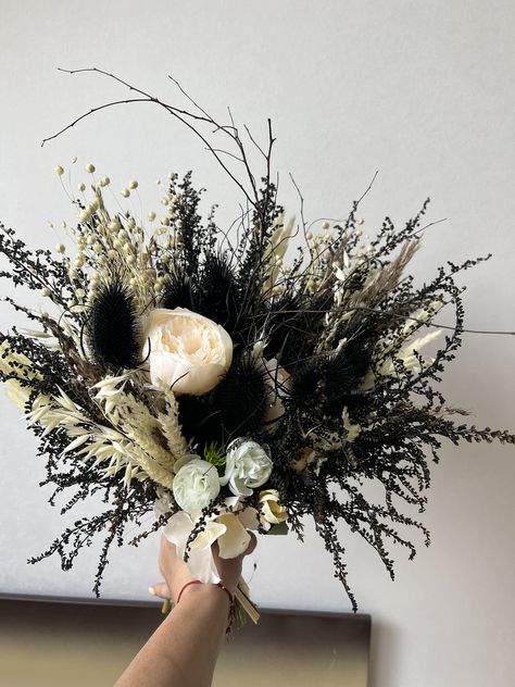 Introducing our exquisite Gothic Black Dried Flower Bouquet, a truly unique and captivating choice for your Gothic wedding. This striking bridal bouquet features a mesmerizing blend of black dried flowers, creating a dark and romantic aesthetic. Each bloom has been carefully preserved, retaining its natural beauty and delicate charm. The contrasting colors and textures of the dried flowers make this bouquet truly one-of-a-kind, adding an enchanting touch to your wedding ensemble. Displayed in an elegant vase, our dried flower arrangements provide a lasting and low-maintenance option for adding a touch of elegance to any space. Embrace the allure of Gothic aesthetics with this stunning black bouquet, a perfect choice for those seeking a distinctive and unconventional wedding theme. About bo Dark Moody Wedding Bouquet, Black Dried Flowers, Goth Wedding Flowers, Dark Flower Arrangements, Black Bouquet Wedding, Gothic Flower Bouquet, Dark Wedding Bouquet, Black Flowers Bouquet, Flower Arrangements In Vase