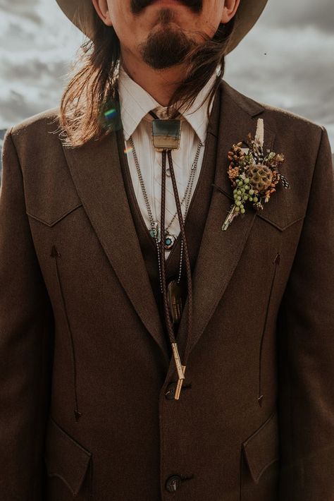 Western inspired wedding day attire for this stylish boho groom. | Photo by Maggie Grace Photography #westernwedding #bohowedding #wedding #mountainwedding #boho #bohogroom #groom #groomfashion #poseideas #groompose #groomportrait #bolotie #weddingcolors #fall #fallwedding Mens Wedding Attire Woods, Vintage Wedding Attire For Men, Boho Tuxedo Men, Men’s Vintage Wedding Attire, Bohemian Mens Wedding Attire, Groom Vintage Attire, Woodsy Groom Attire, Hobbit Wedding Groomsmen, Western Wedding Suits Groom