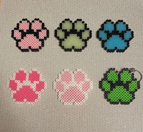 Hand made paw print piece that can be used as a coaster, wall decor or turned into a keychain. Each paw print is approx.2.5 inches long. (Made out of perler beads.) Note: * Keychain option means a chain and keyring will be added to the side of chosen paw piece. This option is great if you don't want to use the product as wall decor/ coaster. (approx 4.5 inches long with chain)  *When you purchased a paw as a wall decor you will receive a command strip to help the item stick to surfaces.  *When you select the option none in the add on box, this means you would like the product as a coaster.  *The colors with GID mean the paws glows in the dark after being activated by a bright light (flashligh/ phone light) for a few minutes. Perler Bead Patterns 15x15, Diy Perler Beads Ideas, Fuze Beads Ideas Easy, Paw Print Perler Bead Patterns, Paw Print Perler Beads, Cool Perler Beads, Perler Bead Keychain Pattern, Pearl Or Beads Ideas, Perler Chain