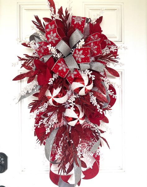 "Your door will be stunning this Christmas decorated with this beautiful red, white, and silver swag.  This teardrop swag is loaded with lots of glitz and glam and features three red and white shatterproof ball ornaments.  The double ribbon bow is made of a solid silver glittered ribbon and red and silver snowflake print velvet ribbon.  The swag is accented with red glittered leaves and white glittered berries throughout.  This charming wreath has a glamorous, show-stopper appeal and would be a Red And White Christmas Swag, Teardrop Swag Christmas, Swag Wreaths For Front Door, Diy Swag Wreath, Christmas Swags For Front Door, Christmas Swag, Christmas Swags Ideas, Diy Swag, Blue Christmas Tree Decorations