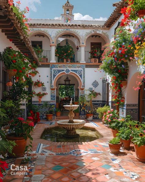 Discover the vibrant hues of this Andalusian courtyard, featuring an inviting fountain and lush potted plants. The stunning tile patterns and hanging flowers make it an ideal spot for relaxation. Follow CasaCampera for more courtyard decor ideas! Architecture With Courtyard, Courtyard Window Design, Traditional Courtyard Design, Moroccan Style Courtyard, Italian Villa Garden Courtyards, Small House Courtyard, House With Courtyard In The Middle, Arab Courtyard, Indian Courtyard House