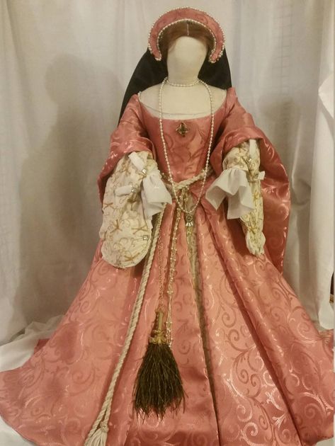 This is a Fashion Doll of Princess at age 13 to 15 in a beautiful coral pink gown.  She is 3 feet tall and 3 feet wide at her hem.  with a 15 inch waist she is the top of Tudor Fashion. The doll, her stand and every part of her even the wig are handmade to recreate the Nobility and Romance of the 1550's. Golden dragon flies adorn her sleeves and underskirt.  A to scale peacock fan hangs from her waist.   Stockings, chemises, corset, hoop, petite coat, skirt, gown, fore sleeves and french hood, wig  with girdle and jewelry to match. This is a one of a kind Doll.      The first in a series that will only number 10. Pink Medieval Dress, Peacock Fan, Tudor Gown, Era Victoria, Tudor Dress, Tudor Fashion, Tudor Costumes, Old Fashion Dresses, Princess Elizabeth