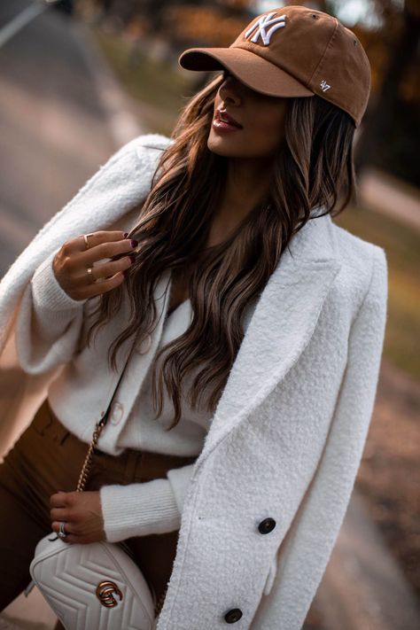 Fashion blogger mia mia mine wears a gucci crossbody bag outfit with an ivory coat and brown coated jeans. click through to see more casual weekend outfits for winter, how to wear a baseball cap, jeans and sneakers outfit, and cozy cardigan outfits. #casualootd #gucci #womensfashion #outfitinspo Lisa Vidal, Cap Outfits For Women, Winter Cardigan Outfit, White Coats, Baseball Cap Outfit, Coated Jeans, Mia Mia, Cap Outfit, Looks Pinterest