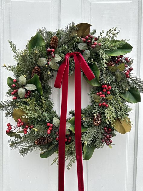 This classic evergreen Christmas wreath is a beautiful statement piece for the holiday season. It is made on a pine wreath base with high quality cedar foliage, magnolia leaves, pine needles and pinecones, burgundy berries, and finished with a gorgeous burgundy velvet bow. It would look fantastic hanging on any door, over the mantle, or on a wall or mirror in your home. It would also make a great gift for housewarming, weddings, birthdays, or anniversaries! Each wreath is hand crafted by Boles Family Creations for you upon ordering.  This wreath is approximately 24-25 inches in diameter from leaf tip to leaf tip. It is made on a 24 inch evergreen wreath base. PLEASE NOTE: Each item is custom made and will vary slightly from the pictures shown. Grapevine wreaths are natural products and wil Christmas Wreaths For Door, Gorgeous Christmas Wreaths, Neutral And Burgundy Christmas, Christmas Wreath Mantle, Evergreen Christmas Wreath, Fresh Evergreen Wreaths, Ralph Lauren Christmas Wreath, Burgundy Wreaths For Front Door, Holly Berry Christmas Decor