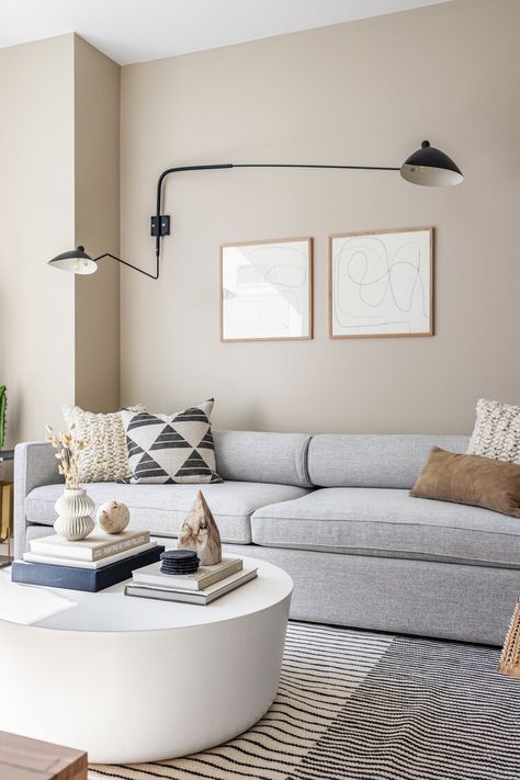 Neutral living room with beige walls, grey sofa, white concrete coffee table, abstract wood framed art and black double sconce above sofa. Living Room Design Beige, Couch Grau, Greige Living Room, Gray Sofa Living, Grey Walls Living Room, Grey Sofa Living Room, Beige Room, Living Room Wall Color, Room Wall Colors