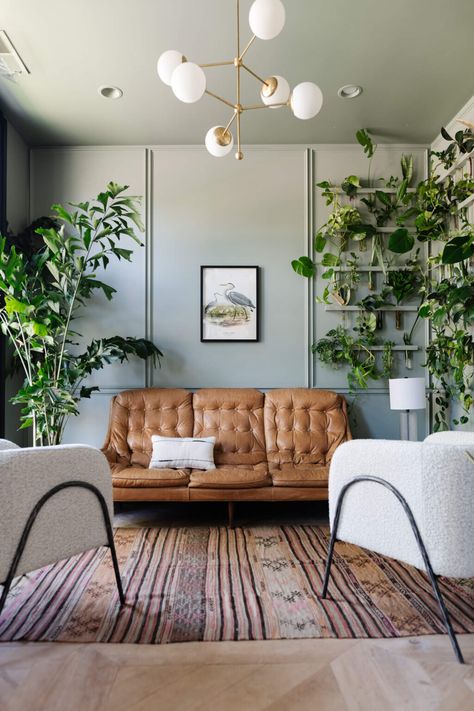 Wall painted Sherwin Williams color of the year 2022 Evergreen Fog with tan leather couch and large plants 2022 Color Of The Year, Fleetwood Paint, Salon Suites, Vintage Revival, Leather Couch, Popular Color, Living Room Paint, Room Paint, Color Of The Year