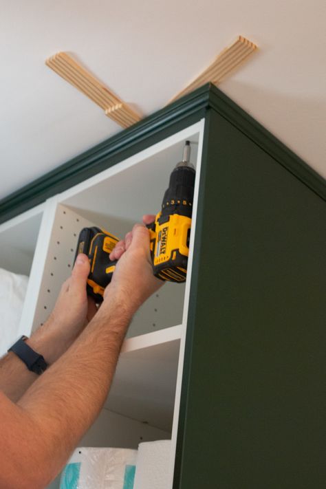 Adding crown molding to the ceiling. Come learn our tips for installing IKEA kitchen cabinets and making them look high-end and built-in. We used these dark green cabinets in our laundry room and they turned out absolutely gorgeous! #IKEA #ikeakitchen #DIYkitchencabinets Ikea Upper Cabinet, Ikea Kitchen Laundry Room, Crown Molding On Ikea Kitchen Cabinets, Ikea Kitchen Cabinet Hacks Built Ins, Ikea Crown Molding, Wall Kitchen Cabinets Ideas, Upper Cabinet Molding, Ikea Kitchen Crown Molding, Ikea Sektion Axstad Kitchen