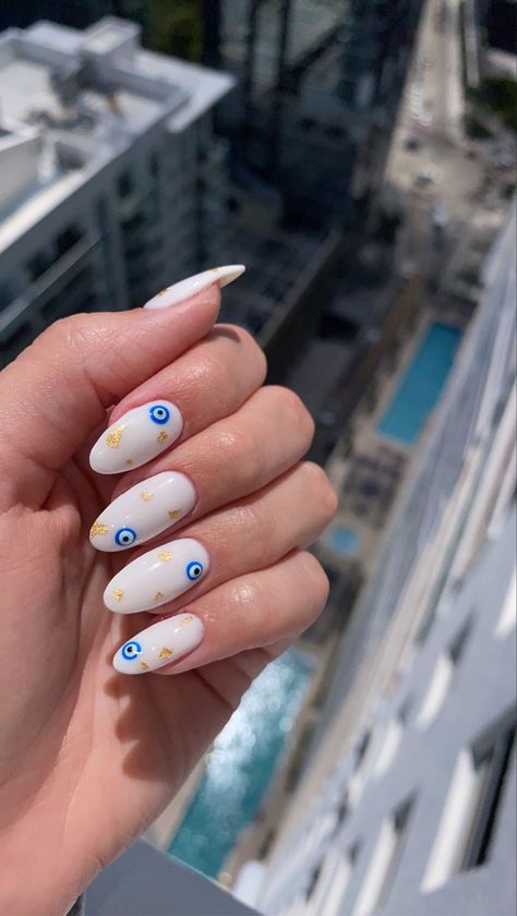 Greece evil eye gold flakes mani pedi nail manicure design trendy summer nails white sleek classic classy hot beach spring trending Europe vacation vacay Miami Greek inspo inspiration Blue Eye Nail Art, Trendy Nails Evil Eye, Nail Design With Evil Eye, Almond Nails French Tip Evil Eye, Eye Nail Art Evil, Evil Eye Nails With Gold, Evil Eye Nails Almond Shape, White Nails Evil Eye Design, Devils Eye Nails