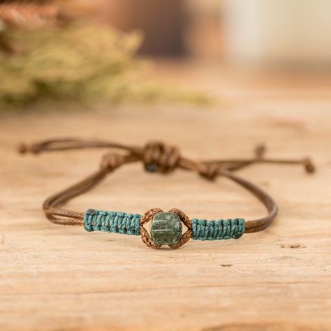 The star of the show in this fashionable men's bracelet is a captivating dark green jade pendant that takes center stage with its exotic allure. Expertly accented with intricate waxed cotton macrame detailing in a vibrant teal hue, Guatemalan artisans Erick and Ivania's impressive design seamlessly fuses tradition and contemporary flair. Its adjustable brown nylon cord ensures a tailored fit, allowing you to wear this accessory with ease and comfort. Chinese Cord Bracelets, Macrame Jade Necklace, Cheap Green Jewelry With Sliding Knot, Jade Bracelet Design, Corded Bracelets Diy, Diy Bracelet For Men, Crochet Bracelet For Men, Macrame Bracelet Patterns Easy, Macrame For Men