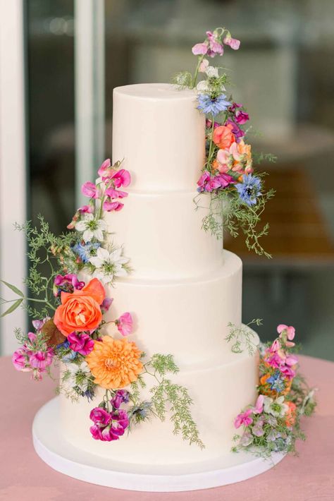 The tiered wedding cake with flowers in bright blue, coral, pink and orange with delicate greenery. Wedding Dessert Table Colorful, May Wedding Food Ideas, Ethereal Spring Wedding, Italian Vineyard Wedding Aesthetic, Spring Floral Wedding Cake, 3 Tier Wedding Cake With Flowers, Tiered Wedding Cake With Flowers, Altar Flower Arrangements, Summer Wedding Cake Ideas