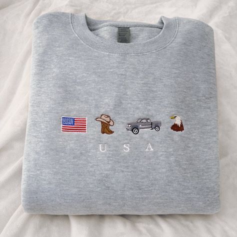 Extra soft and oversized USA embroidered sweatshirt. Why it's special 🇺🇸 * Embroidery: Premium "USA" stitching with classic symbols: the beloved American flag, cute cowboy boots & hat, a pickup truck, and a the iconic bald eagle. * Oversized fit: Comfy & casual for the perfect fit * Material: Extra soft, cotton-poly in Dark Black * Color: Dark Black or Soft Gray * Easy Care: Machine-washable, gentle cycle, hang to dry * Embroidered in the USA Don't miss out on the most American crewneck on Ets Cowgirl Truck, Usa Embroidery, Darkest Black Color, Clothes Embroidery Diy, Boots Cowboy, Embroidery Sweatshirt, Embroidered Crewneck, Embroidered Sweatshirt, Animal Fashion