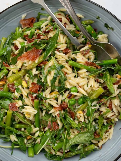 Orzo salad with spring vegetables like asparagus, peas, arugula, and fresh herbs. The surprise element is crispy prosciutto that elevates this humble salad to an elegant one. Asparagus Arugula Salad, Orzo Arugula Salad, Orzo Arugula, Pasta Salad With Asparagus, Arugula Pasta, Crispy Prosciutto, Spring Veggies, Breakfast Appetizers, Asparagus Salad