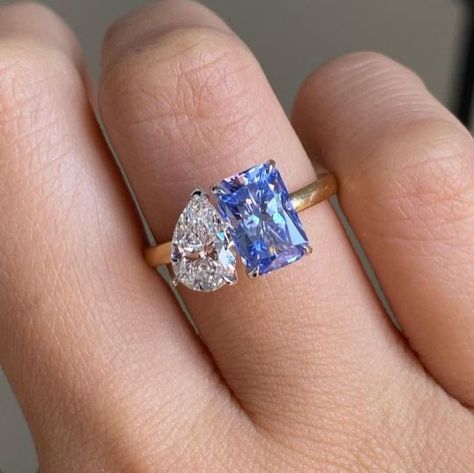 The Blue Moissanite adds a unique and colorful touch to the traditional toi et moi designs. A radiant and pear cut moissanite ring combines two different shapes of moissanite stones in one ring. A unique cathedral set two stone ring is another type of two stones are set on either side of the ring's band. This style is a great choice for those who want a non traditional and eye catching engagement ring. All three designs offer unique and beautiful ways to symbolize your commitment to your partner Real Diamond Engagement Rings Unique, Two Stone Engagement Ring Sapphire, Double Gem Engagement Ring, Two Gemstone Ring, Two Stone Engagement Rings, Double Engagement Ring, Double Diamond Engagement Ring, Multi Stone Engagement Ring, Purple Engagement Rings