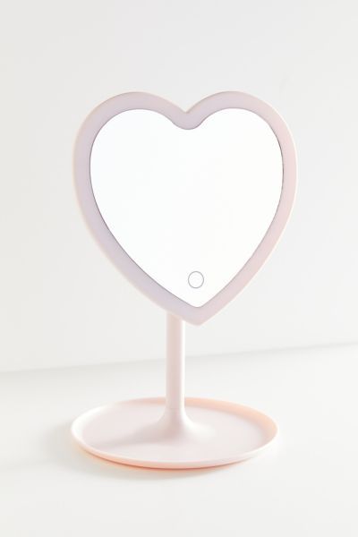 Show your shelf some love with this standing LED mirror in the shape of a heart. Features a catch-all tray base to store your favorite jewelry, makeup and skincare. Exclusively available at UO.Features. LED light Smart touch button Storage tray for accessories 180° rotation Battery operated (requires 3 AAA batteries)Content + Care. 100% Plastic Wipe clean ImportedSize. Dimensions: 7.7”w x 11.4”h Heart Makeup Mirror, Small Light Up Mirror, Cute Makeup Mirror, Small Mirror With Lights, Mirrors For Desk, Desk Makeup Mirror, Cute Desk Mirror, Purple Room Accessories, Cute Pink Room Decor