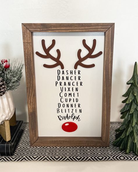 This 3D and laser engraved Reindeer name sign is the perfect addition to any Christmas decor. It is made to stand on its own so it styles well on entry tables, counter tops, shelves, mantles, etc. It has about 1/2 inch over hang that would allow it to hang on walls as well.  Materials: The frame is made from premium pine The Sign is made on a high quality MDF backer board with engraved lettering and laser cut acrylic antlers and nose The Sign pictured is 8x12 THE SIZE IS THE ENTIRE SIGN TOP TO BOTTOM INCLUDING THE FRAME *NO HANGING HARDWARE IS INCLUDED **PLEASE NOTE THAT EACH PIECE OF WOOD HAS DIFFERENT NATURAL CHARACTERISTICS SUCH AS CRACKS, KNOTS AND TEXTURE. THIS CAUSES SLIGHT VARIATIONS IN HOW THE STAIN ABSORBS. EACH FRAME IS UNIQUE. Signs For Christmas, Diy Christmas Board Signs, Christmas Picture Decor, Diy Christmas Wall Art Craft Ideas, Christmas Wall Collage Ideas, Shelves Christmas Decor, Xmas Signs On Wood, Reindeer Themed Christmas Decor, Christmas Cricut Signs