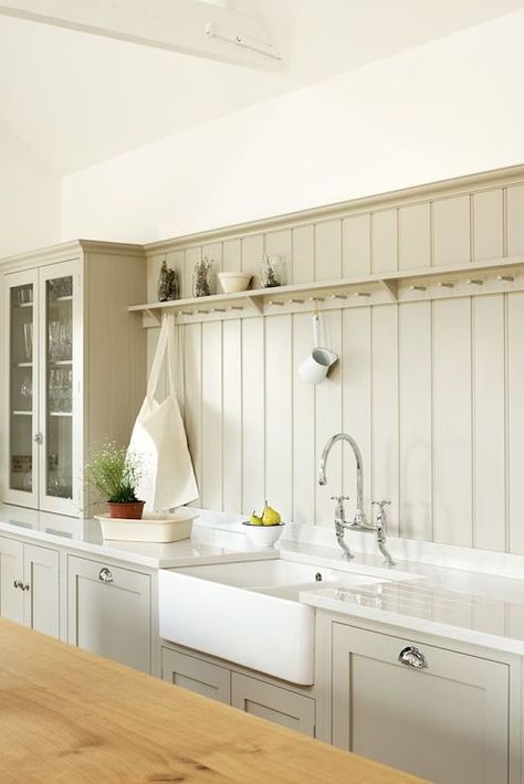 Stunning grey colored kitchen with custom shaker cabinets adorned with cup pull hardware alongside a dual farmhouse sink with bridge faucet framed by white stone counters which pair with a gray tongue and groove backsplash accented with cup hook shelf beside a countertop glass front hutch. Shaker Kitchen, Kitchen Devol, Single Pane Windows, Treads And Risers, Plywood Panels, Woodworking Supplies, Wood Panel Walls, Home Upgrades, Wide Plank