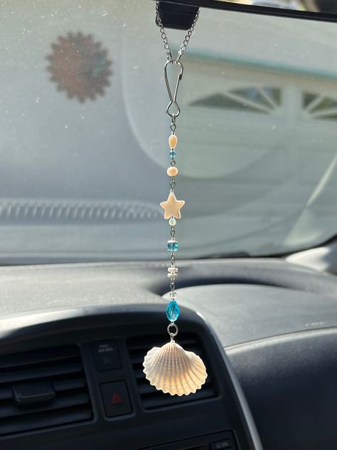 Coastal Car Charm 🌊 This is my FAVORITE charm at the moment <3 looking at it hang in my car makes me feel like i'm driving to the beach <3 I hand drilled the shell & put lots of love into this design <3 Made with Stainless steel findings * Glass beads * Shell beads * Cultured pearl  Ideas on what to use it for: - Rear view mirror charm - Window decor (The charms look so beautiful when the sun hits them!) - Wind chime / Outside decor - Room Decor - Anything you wish to decorate <3  Every charm is designed and made by me. Since it's made-to-order, you'll be receiving a charm that was handcrafted specifically for you 💌   This charm includes small stones, and glass beads that are delicate. It will be packaged in bubble wrap but it is important to handle this (and all other charms) with care Homemade Car Accessories, Car Accessories Hanging, Ocean Car Accessories, How To Make Car Charms Rear View Mirror, Decorating Car Ideas, Diy Rearview Mirror Charm, What To Make With Shells, Diy Car Charms Rear View Mirror, Diy Car Charms