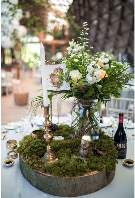 a woodland wedding centerpiece of a wood slice, moss, blooms and greenery in a jar, feathers and candles Boho Chic Forest Wedding, Moss Decorations Wedding, Moss Table Wedding, Woodland Theme Centerpieces Decor, Woodland Fairy Wedding Table Decor, Nature Themed Table Decor, Moss Decor Wedding, Moss Table Centerpiece, Woodland Table Centerpieces