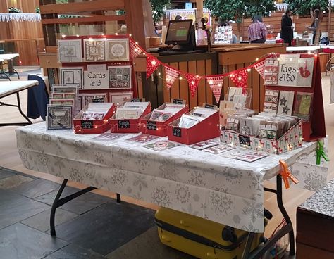 Simple DIY greeting cards craft stall using old cardboard boxes wrapped in red paper & homesewn bunting using fabric scraps. The whole setup cost under £10 Paper Craft Booth Display Ideas, Christmas Craft Stall Display, Display For Greeting Cards, Christmas Stall Display, Craft Show Booth Display Ideas For Greeting Cards, Christmas Craft Stall Display Ideas, Greeting Card Market Display, Christmas Craft Stall Ideas, Christmas Craft Stall