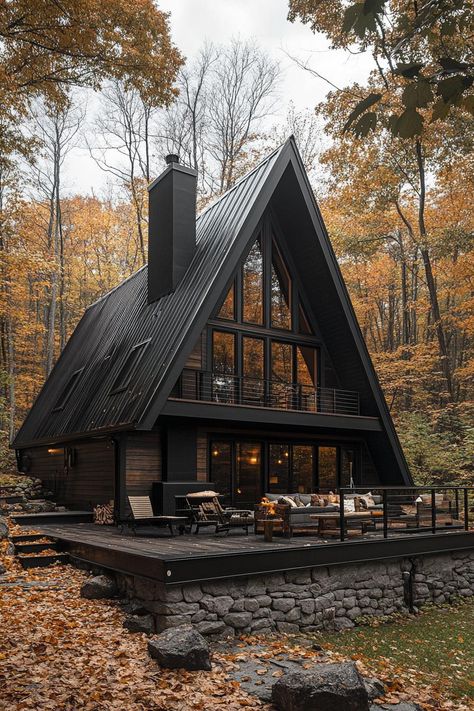 Large a frame house with charred wood siding black metal roof with black chimney stone foundation with front deck with outdoor furniture house. Check out all of these stunning and chic dark A-frame houses that pack a ton of charm into a small forest retreat.