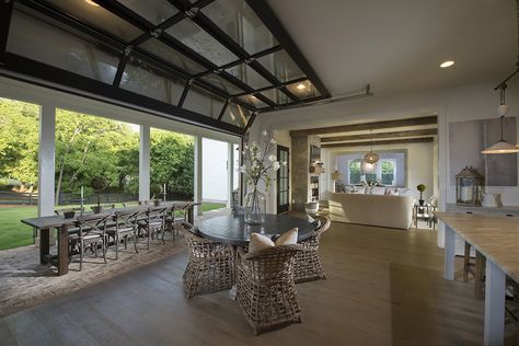 A stunning glass roll-up door connects this kitchen to the outdoor dining area beyond. Roll Up Glass Garage Doors, Roll Up Glass Doors In House, Outdoor Kitchen Garage Door, Glass Roll Up Door, Large Outdoor Entertaining Area, Roll Up Doors For Patio, Roll Up Doors In House, Glass Garage Doors In House, Glass Garage Door Patio