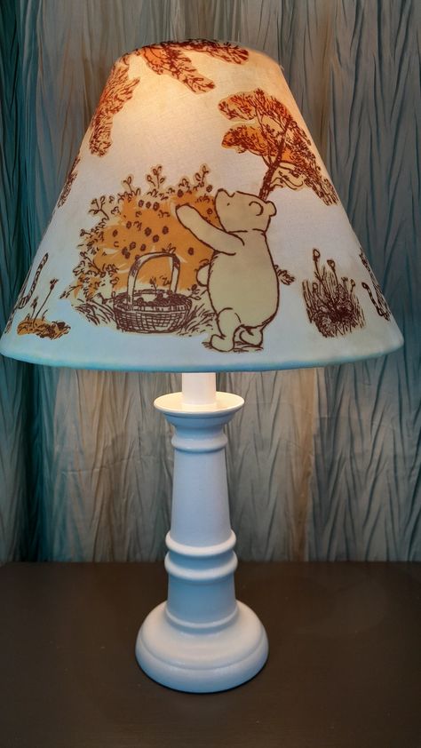 This sweet Winnie the Pooh Nursery accent lamp features first a hand dyed cotton cream/yellow and white fabric, covered with fabric appliques of Pooh, Tigger, Eeyore, Piglet, and Christopher Robin. The shade fits on any lamp base, sitting on the socket above the light bulb on a suspended ring. The shade itself measures 7 1/4 in High by 10 in wide and fits a base up to 12 in in height. The shade can be purchased alone, or with the lamp base. The assembled lamp offered is 15 and a half inches tall. The hand painted and sealed base comes in your choice of white or cream. Base color options can be viewed in the photo gallery. What a perfect gift this would make for any baby's Winnie the Pooh nursery. Winnie The Pop Nursery, Nursery Ideas Pooh Bear, Old Winnie The Pooh Nursery, Winnie The Pooh Nursery Ideas, Winnie The Pooh Baby Nursery, Vintage Winnie The Pooh Nursery, Pooh Bear Nursery, Nursery Winnie The Pooh, Winnie The Pooh Nursery Decor