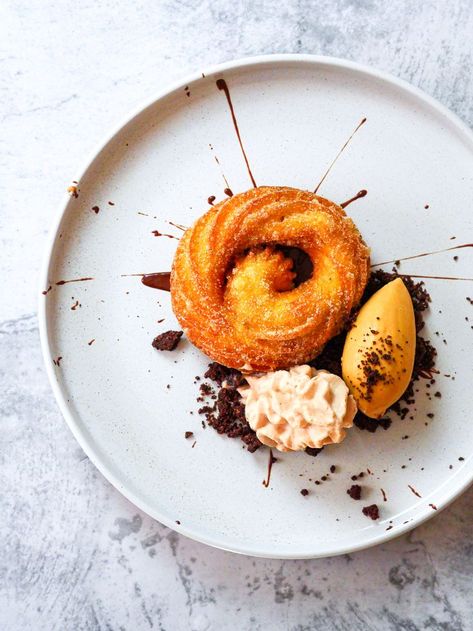 Churro Plated dessert There's just something about the crispy and doughy texture, the cinnamon sugar coating, and the way they're so perfect for dipping into chocolate that makes them irresistible. And now there's a new way to enjoy these delicious treats: as a plated dessert. Served with a “burnt” sugar ice cream, miso chocolate espuma, and a bitter chocolate sauce, it makes them even more irresistible. A super-easy plated dessert Dessert Recipes For Restaurants, Food Plating Dessert, Restaurant Plated Desserts, Simple Plated Desserts, Ice Cream Plated Dessert, Churros Presentation Ideas, Sauce Plating Ideas, Churros Plating Ideas, Easy Plated Desserts Ideas