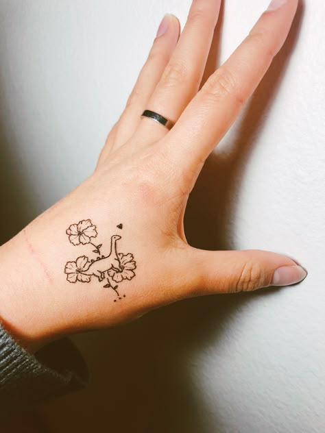 Dainty dinosaur tattoo with hibiscus flowers! Womens Dinosaur Tattoo, Dinosaur Tattoo For Daughter, Dino Flower Tattoo, Cute Dinosaur Tattoos For Women, Pretty Dinosaur Tattoo, Dino With Cowboy Hat Tattoo, Matching Dinosaur Tattoo Best Friends, Dinosaur Holding Knife Tattoo, Dinosaur Hand Tattoo