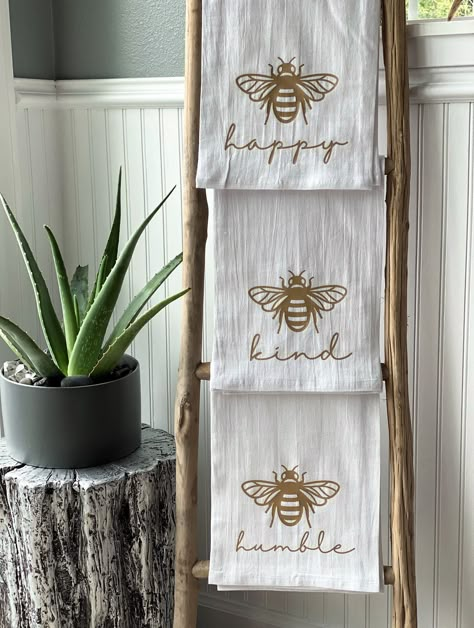 "These handmade kitchen tea towels are the perfect way to change up your kitchen décor! They also make thoughtful hostess,  housewarming and wedding gifts!  This set features the designs  \"Bee Happy,\" \"Bee Humble,\" and \"Bee Kind\" in metallic gold.  Material: 100% cotton Measurements: 28\"x28\" Care Instructions: machine wash cold, gentle cycle. use non-chlorine bleach only. Tumble dry low. Warm iron if needed.  Matching accessories can be found here: https://www.etsy.com/shop/HobsonHandbags?ref=seller-platform-mcnav&search_query=bee Do you have a custom design mind? Send a private message to initiate a custom order request! ❤ All items are handcrafted by Desiree Hobson, Owner/Designer/Maker ❤ Follow on Instagram at @hobshandbags or on TikTok at @hobsonmade for a behind the scene glim Bee Kitchen Theme, Humble Bee, Honey Bee Decor, Bee Inspired, Bee Kind, Rustic Kitchen Decor, Bee Crafts, Gold Bee, Bee Decor