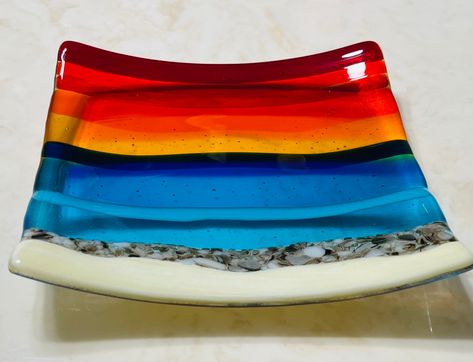 "Fused glass beach sunset plate with French Vanilla for the sand, White and Brown for the rocks by the water, Turquoise and Blue for the ocean waves, and Yellow, Orange, Red sunset skies. This dish has an additional layer of clear glass on the back for a more elegant look and for creating the beautiful bubbles effect. Please note that all my items are Handmade so there may be slight color and / or design variations. A beautiful plate, reminds me of my favorite place to be! Perfect for decorati Fused Glass Sunset, Fused Glass Beach, Beach Dessert, Ocean Soap, Sunset Skies, Glass Fusing Projects, Glass Beach, Red Sunset, Tea Bag Holder