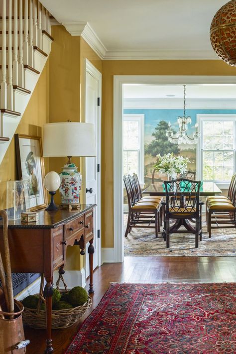 Robin Henry filled this 1910 farmhouse with an array of antiques but made sure it didn't skew too traditional with unexpected colors, fresh accents, and bold pattern mixing. Glossy honey-colored walls create a warm welcome. Foyer Wall Colors Entry Ways, 1910 Farmhouse, Black Painted Walls, Cement Tile Floor, Red Color Combinations, Entryway Benches, Westchester Ny, Chic Mirror, Entry Ways