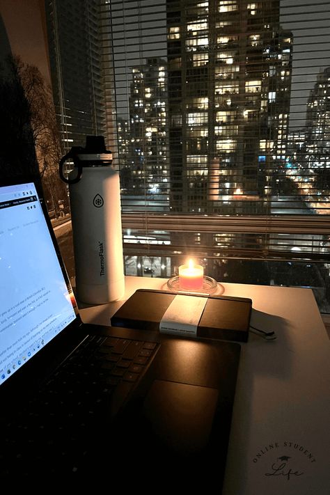 An open laptop on a desk beside a candle and planner with a nighttime cityscape in the background. Working Late At Night Aesthetic, Night Office Aesthetic, Night Time Routine Aesthetic Photos, Working At Night Aesthetic, Writing At Night Aesthetic, Early Adulthood Aesthetic, Night Time Study Aesthetic, Late Night Studying Aesthetic Library, College Night Aesthetic