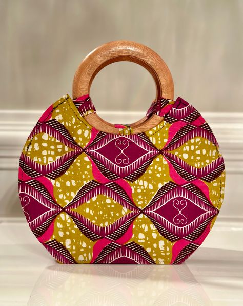 Our handmade hand bag with wooden handle is not big or too small. It’s just the right bag to fit your phone, wallet, and a few personal items. Lined with black fabric. Has an inside pocket. Zip to keep content intact. Wooden handle may vary from picture depending on piece shipped to you. Adepa is the top notch fabric in Ghana! DIMENSIONS;Length - 10 inch Width - 4 inchHeight - 8 inches (12” with handles) care : spot clean Wooden Bag Handles, Sequence Gown Styles, Big Hand Bag, Sequence Gown, Wooden Handle Bag, Bags Sewing, Wooden Bag, African Crafts, Fabric Handbags