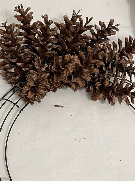 Do you have pinecones in your yard? Go outside, gather them up, and let's make an amazing pinecone wreath for Winter! Tutorial on how to attach pinecones to a wreath form and how to paint it white! Please pin this and follow us for more DIY and seasonal decor inspiration! Big Pine Cones Christmas Decor, Crafts Made With Pinecones, Wire Frame Wreath Tutorial, Small Pine Cone Wreaths, Pinecone Wreath Tutorial, Christmas Wreaths With Pine Cones, Cabin Wreath Ideas, Diy Pinecone Wreath How To Make, How To Make Pine Cone Wreaths