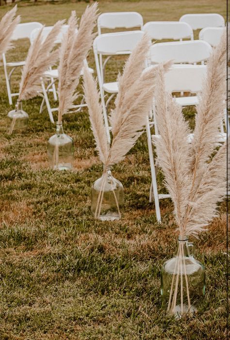 Pampas Grass In Jugs Wedding, Boho Chic Wedding Aisle Decor, Pompous Grass Wedding Decorations, Small Wedding Ideas Western, Pampas Grass Ceremony Decor, Pompis Grass Wedding Decor, Boho Wedding Ideas Decoration Diy, Wine Jug Wedding Decor, Pampas Grass Isle Wedding Decor