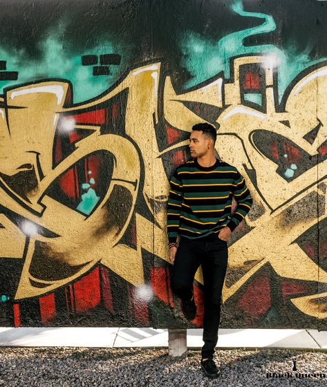 Black male model posing by wall graffiti Wall Poses Photography Men, Wall Poses Instagram Men, Graffiti Wall Photoshoot Men, Grafitti Photoshoot Models, Senior Photos Graffiti Wall, Mural Pictures Poses, Senior Picture Graffiti Wall, Graffiti Photoshoot Ideas Men, Graffiti Wall Photoshoot Ideas