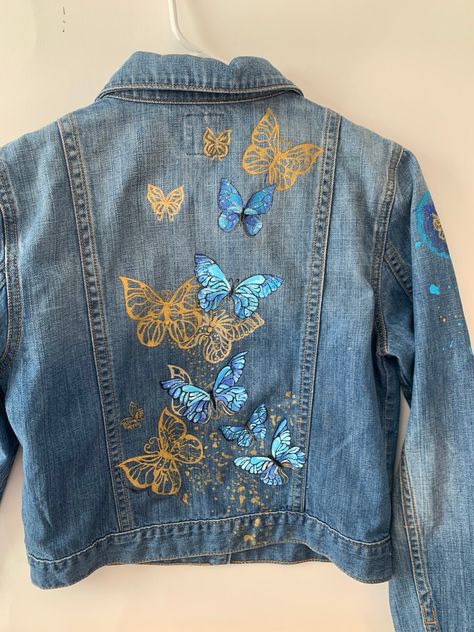 Vintage Denim Jacket from Gap (size M) with hand-painted teal and gold butterflies on the back, a badge on the right sleeve, and abstract paint on front and sleeves.  This jacket is in stock! Customer may send me a jacket to customize, any symbols, any colors. Paint is PERMANENT and WASHABLE.  (Please launder inside-out.) Customer ship personal jacket (or other item, ie, shoes) to me.   I will send back free of charge.   Questions?  Connect with me directly at openhartstudio@gmail.com, or hit the message button further down the screen! Denim Jacket Diy Paint, Butterfly Jacket, Textile Painting, Diy Denim Jacket, Painted Clothes Diy, Hand Painted Denim Jacket, Bling Jeans, Fabric Painting On Clothes, Embellished Denim Jacket