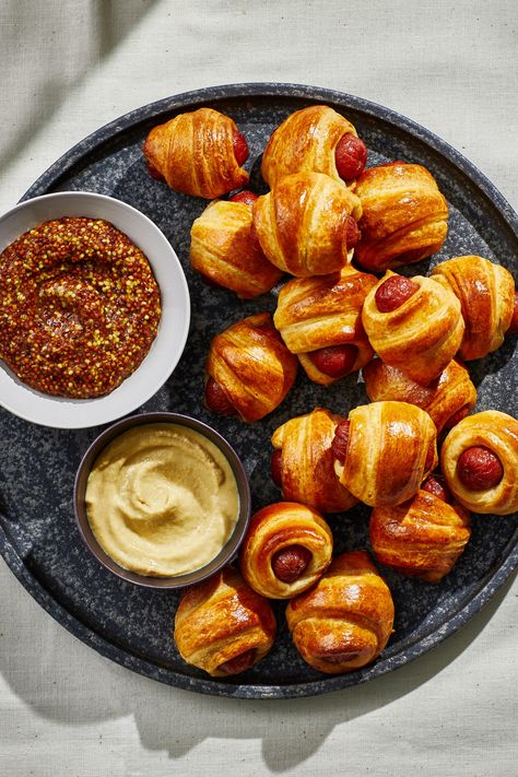 Making the iconic crowd-pleaser doesn’t get easier than with this recipe of mini smoked cocktail sausages (or petit hot dogs) wrapped in store-bought buttery pastry. Prepared crescent roll dough does a lot of heavy lifting here, but you can use puff pastry if you prefer. Served as part of a full-out spread for the Super Bowl, a Monday game day, holiday fête, or weekend get-together, this classic party appetizer will likely disappear as quickly as you put it out, so be prepared to make plenty. Mini Weiner Appetizers, Sausage In Pastry, Croissant Pigs In A Blanket, Croissant Hot Dogs Crescent Rolls, Mini Hot Dogs In Crescent Rolls, Puff Pastry Hot Dog, Crescent Roll Mini Hot Dogs, Sausage Puff Pastry, Easy Pigs In A Blanket