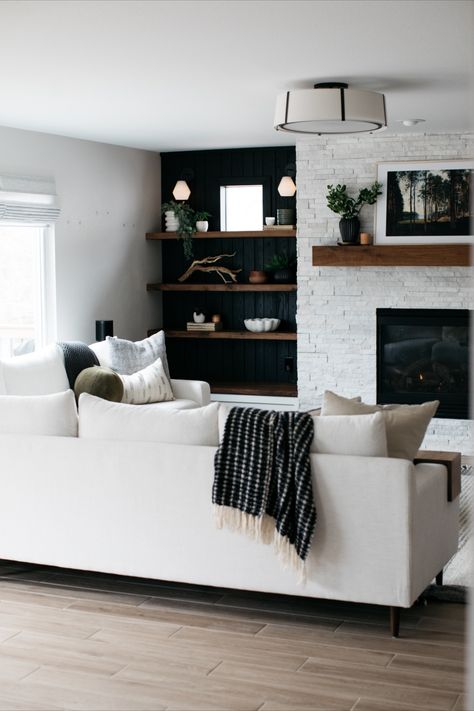 A stacked stone fireplace, black lacquered wall treatments, custom woodwork, gorgeous lighting, and snuggly furniture (the dog agrees ;)... What's not to love in this beautiful transitional/modern style living room?! This one was such a pleasure to design and will stand the test of time for sure. Black White And Dark Wood Living Room, Wood Black And White Living Room, White Fireplace With Grey Walls, Stone And Black Living Room, Dark Wall Light Fireplace, White Fireplace With Black Wall, Pnw Modern Interior, Black Stone Fireplace Wall, Focal Point Living Room Wall