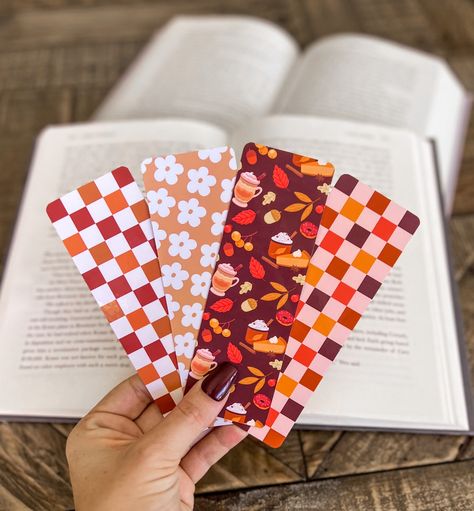 This trendy Fall Bookmark Set is a charming addition to your autumn reading collection. This set features delightful illustrations of Thanksgiving treats, a simple floral design, and a cozy checker print, all designed to infuse the warmth and beauty of the season into your reading experience. Specs: -Measures 2in x 6in -Double sided with a small logo on the back side  -Professionally printed on 350gsm soft touch matte cardstock -Rounded corners  -Laminated bookmarks will have a small border Ship Fall Bookmarks Diy, Diy Fall Bookmarks, Book Marks Design Ideas, Fall Book Marks, Bookish Accessories, Cute Halloween Bookmarks, Fall Bookmarks, Bookmarks Autumn, Autumn Reading