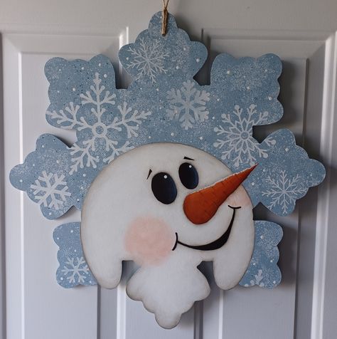 "This happy Snowman is sure to make your guests smile. It would look great on your door for Christmas but can hang out all through the winter months. This adorable door hanger is painted on an 22\" snowflake. If you look close you can see the glitter on his nose and on the snowlakes. We apply several protective coats of acrylic sealer to all of our door hangers to help insure that you'll be able to enjoy your doorhanger for many years." Snowmen Door Decorations, How To Paint A Snowflake, Wooden Snowflakes Painted, Snowflake Door Hanger, Wooden Snowflakes Diy, Snowman Painting On Wood, Wooden Ornament Door Hanger, Christmas Door Hangers Wooden, Paint Snowflakes