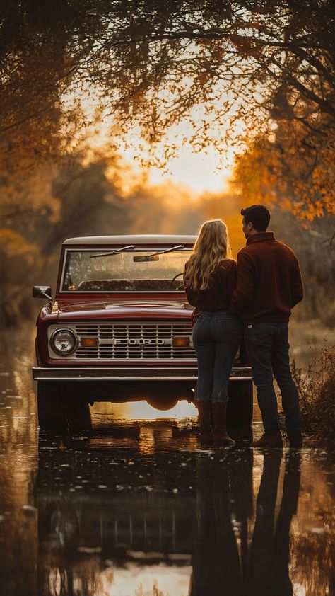 A couple stands together in front of a vintage red Ford truck, surrounded by warm autumn colors and reflections on a calm water surface. The scene captures a romantic and nostalgic fall atmosphere, perfect for outdoor photography and cozy moments. Couples Photoshoot Vintage Romantic, Winter Truck Photoshoot, Old Car Family Photoshoot, Engagement Truck Photos, Couples Photos With Truck, Photos With Old Truck, Truck Pictures Ideas, Cute Fall Couple Pictures Photo Ideas, Couples Truck Photoshoot